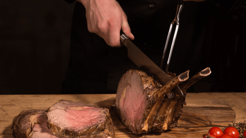 Chef cutting bone in prime rib roast