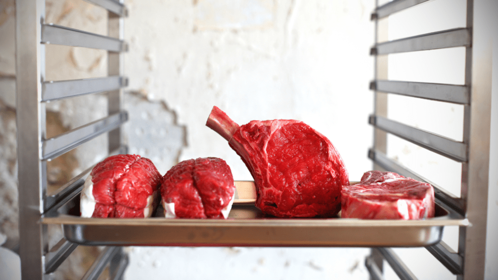 Raw prime rib beef on a rack in a butcher's cooler